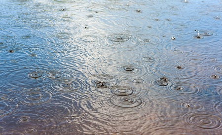 Drops of a sunshower over a lake surfaceの写真素材