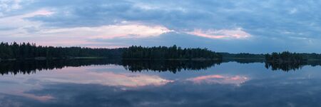 sunset with reflections on the lake in the woodsの写真素材