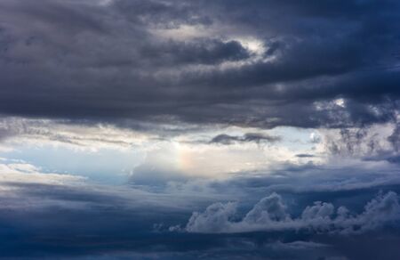 Evening cloudy sky with a small rainbow
