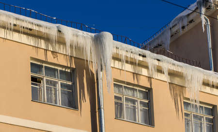 the roof of a residential building with iciclesの写真素材