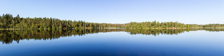 panorama of forest lake with reflections in waterの写真素材