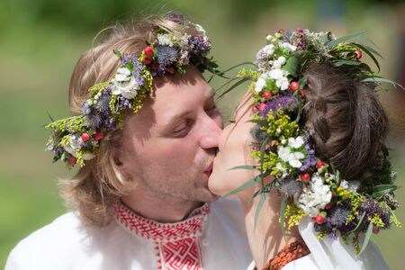 Kiss of the newlyweds in traditional wreathsの写真素材