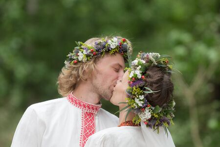Kiss of the newlyweds in traditional wreathsの写真素材