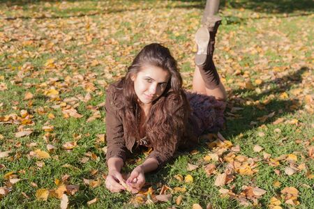 Girl on the lawn with autumn leavesの写真素材
