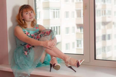 girl in a bright dress on a window sillの写真素材