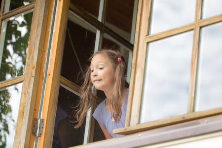 curious girl looks out of the windowの写真素材