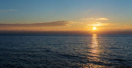 the setting sun on the horizon at seaの写真素材