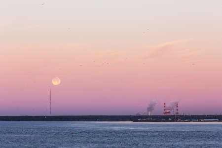 sunrise over the bay with the moon in the skyの写真素材
