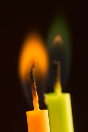 two burning candles in different colors closeupの写真素材