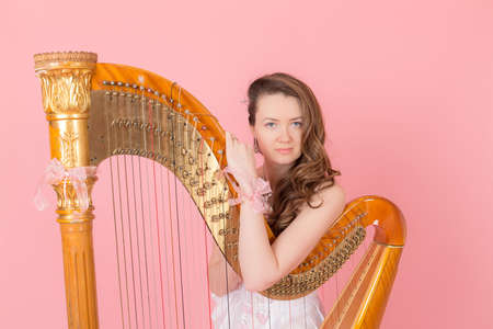 girl with the golden harp on a pink backgroundの写真素材