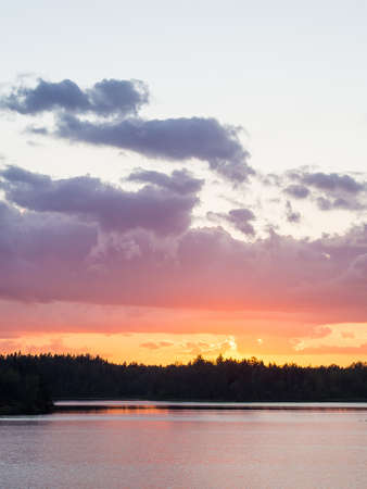 dramatic summer sunset with clouds in forest lakeの写真素材