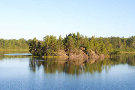 island in the forest lake and reflections in waterの写真素材