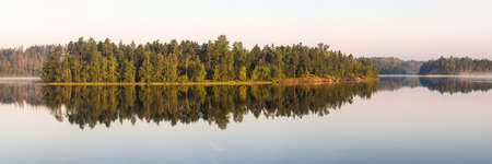 Panorama of forest lake with morning fogの写真素材