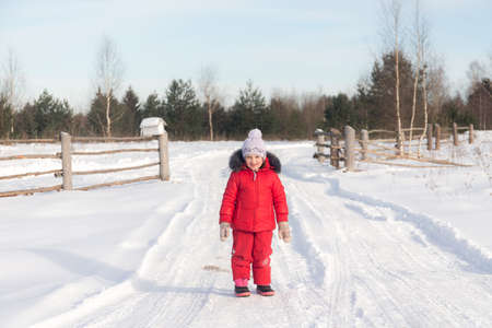 little girl in winter on a rural roadの写真素材