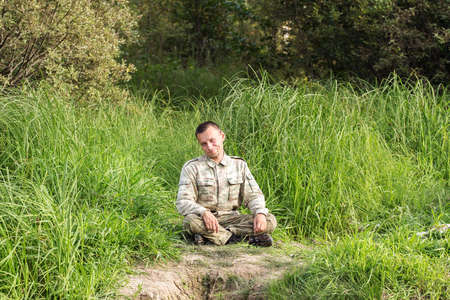 man in camouflage is resting on the grassの写真素材