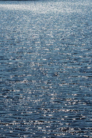 Abstract blue water with ripples and sunlight reflectionsの写真素材