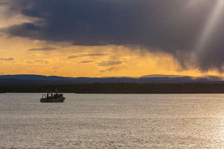 Ship at the shore at sunset with rainの写真素材