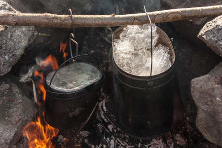 Two tourist pot over the fire in the campの写真素材