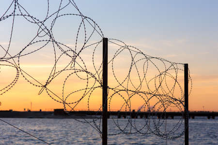 fence of barbed wire near the waterの写真素材