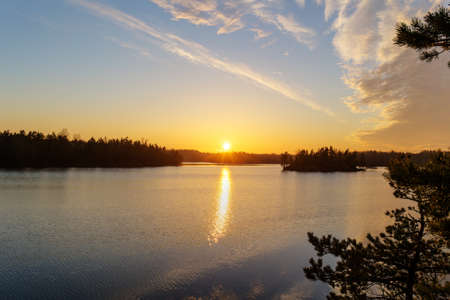 The last rays of the sun at sunset over a forest lake