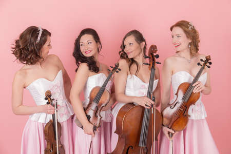 studio portrait of a string quartet on a pink backgroundの写真素材