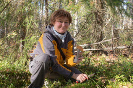 woman picking mushrooms in a sunny autumn forestの写真素材
