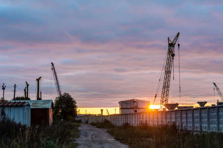 Construction site behind a concrete fence at sunset