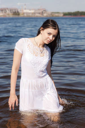 slender girl in white wet dress in waterの写真素材