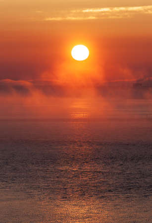 sun at sunset over the sea with fogの写真素材