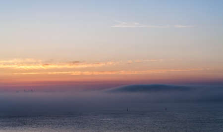 landscape with fog over the sea after sunsetの写真素材