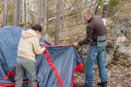 two people set up a tent in a forest campの写真素材