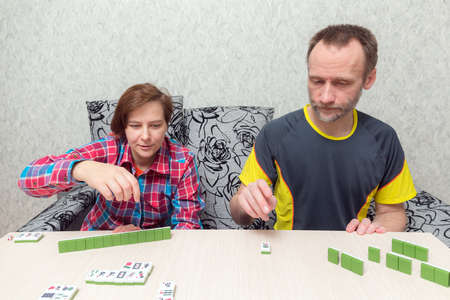 man and woman at the table playing mahjong