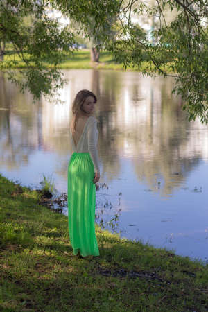 slender girl by the water in a summer parkの写真素材