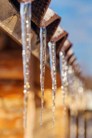 icicles on the roof of a wooden house closeup