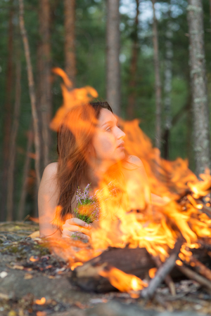 naked girl in the woods near the fireの写真素材
