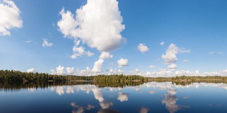 panorama of forest lake with reflections and cloudsの写真素材