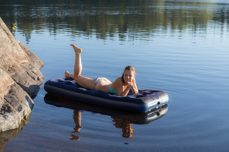 girl lying on an inflatable mattress in the lakeの写真素材