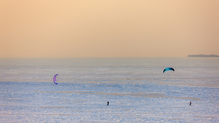 people skiing with a parachute on the ice of a frozen sea bayの写真素材
