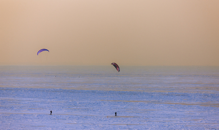 people skiing with a parachute on the ice of a frozen sea bayの写真素材