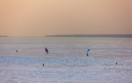 people skiing with a parachute on the ice of a frozen sea bayの写真素材