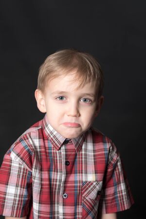 studio portrait of a sad boy on a black background