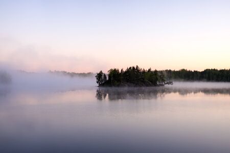 forest lake with morning fog above the waterの写真素材