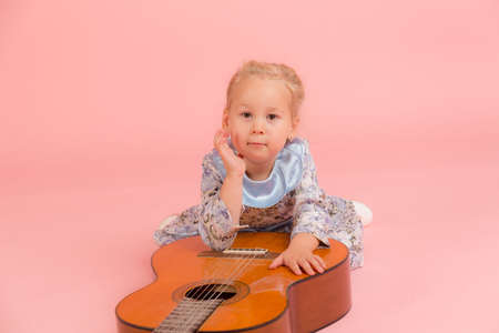 little girl with a guitar on a pink backgroundの写真素材
