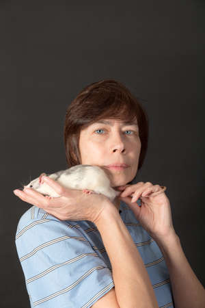 studio portrait of woman with domestic rat on black backgroundの写真素材