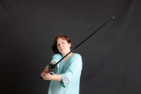 studio portrait of a woman with a sword on a black background