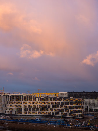 sunrise with pink clouds over the city and construction site
