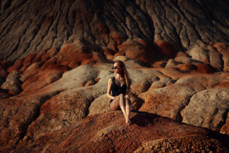 Young beautiful girl posing outdoor on colourful rocky landscapeの写真素材