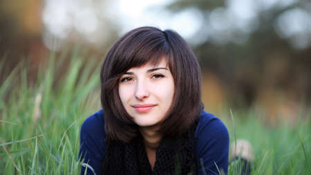 Portrait of young beautiful woman lying in green summer fieldの写真素材