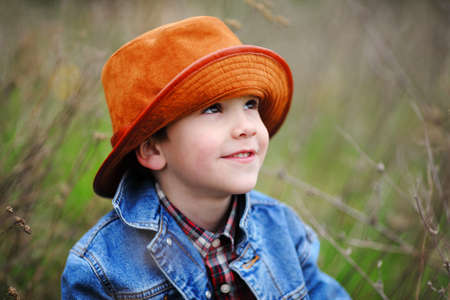 Happy smiling boy dressed in country style playing in the park near sunset with shallow depth of field and copy space to left and right の写真素材