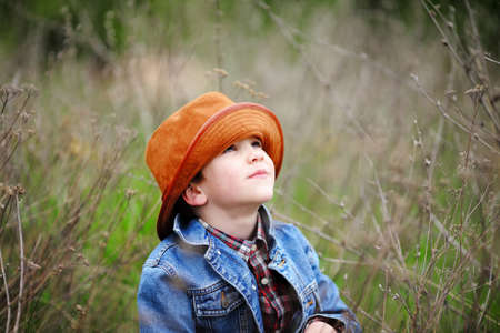 Happy smiling boy dressed in country style playing in the park near sunset with shallow depth of field and copy space to left and right の写真素材